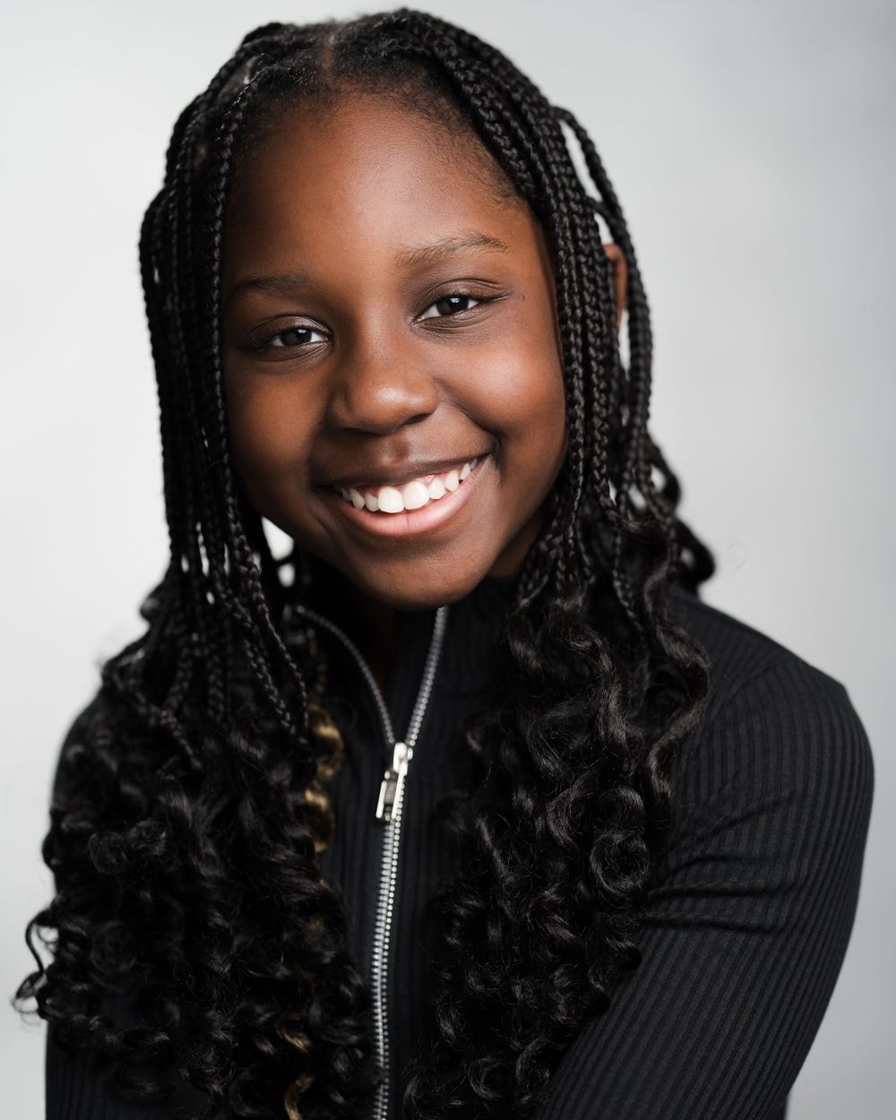 Studio portrait showing bright smile and beautiful braided hairstyle against light background. Children's headshots Surrey.