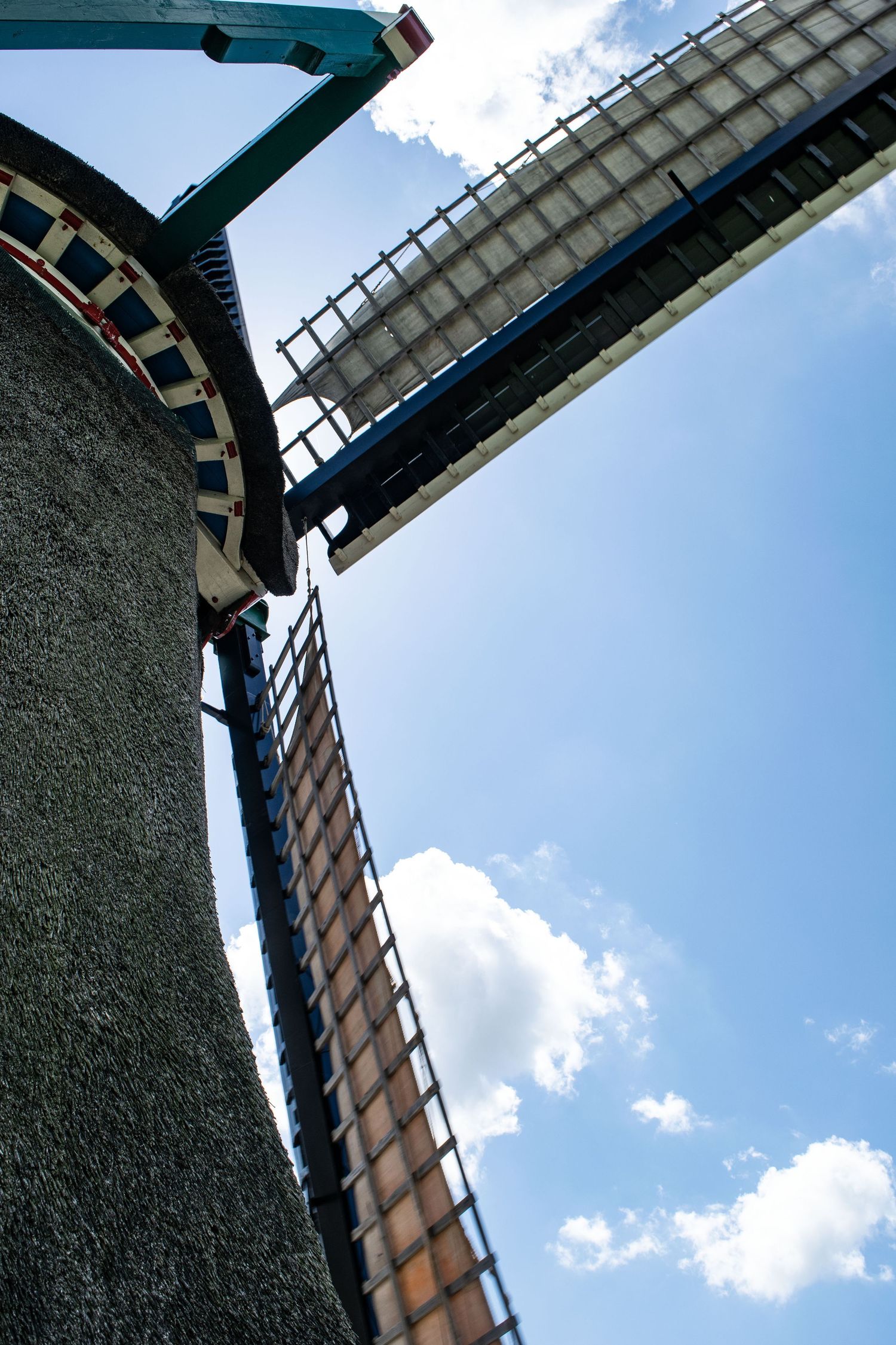 Low angle view of a traditional windmill against blue sky with white clouds.