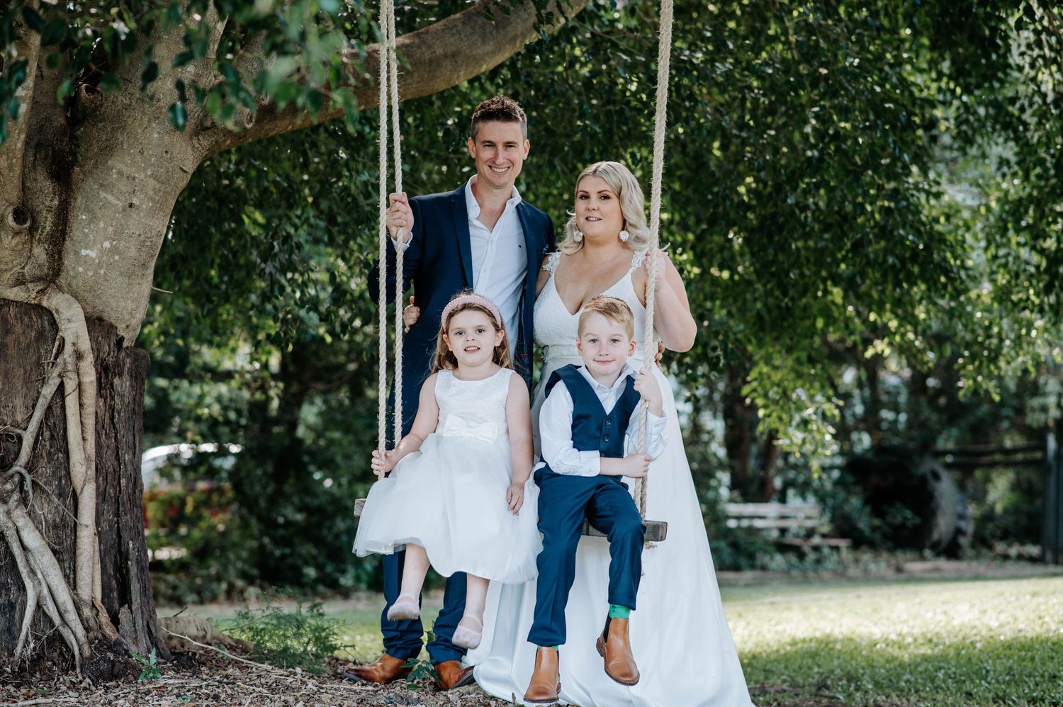 A wedding portrait on a tree swing in a garden setting with natural lighting.