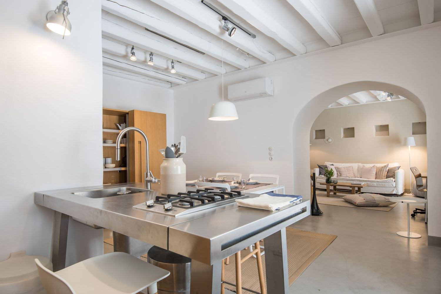 Modern open concept kitchen with stainless steel appliances and arched doorways leading to living area.