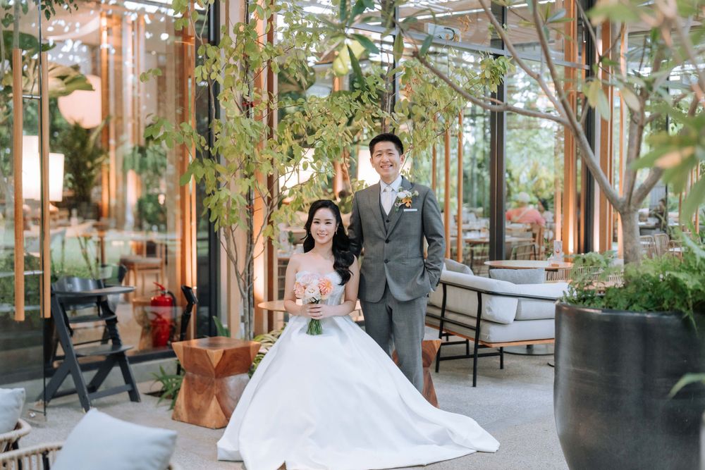 Wedding couple poses in a modern glass-enclosed garden space.