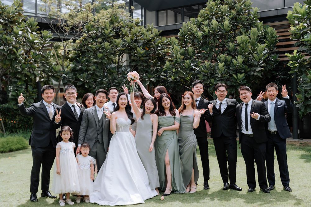 Wedding party poses together for group photo in garden setting.