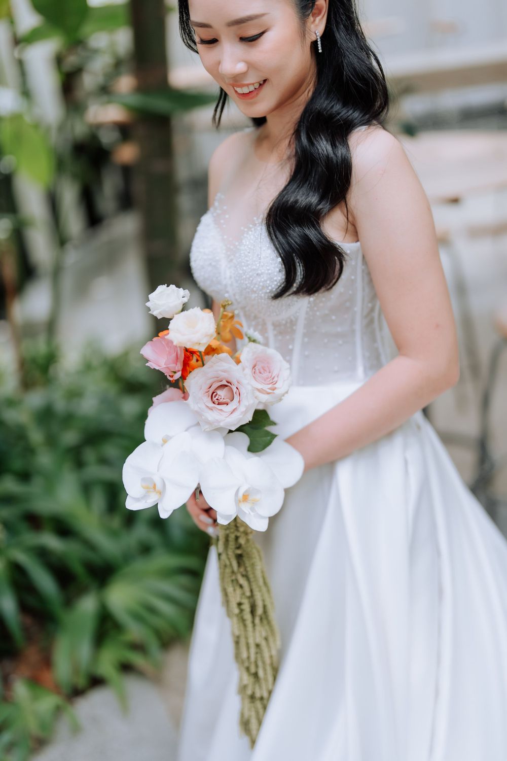 A close-up of a bride holding an elegant bouquet of white orchids and pink roses.