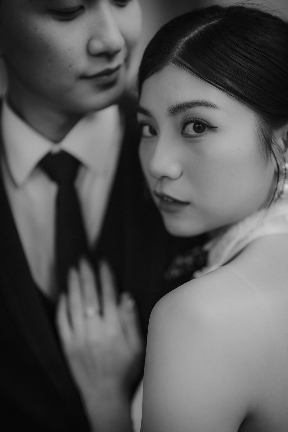 An artistic black and white portrait capturing a romantic wedding couple moment.