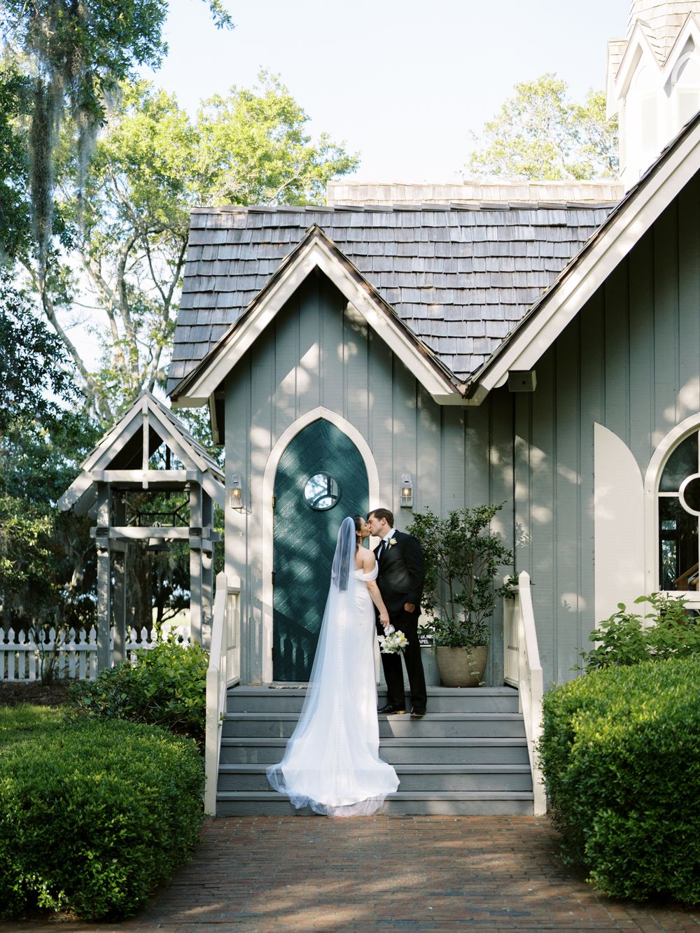 A couple shares an intimate moment on the steps of a charming chapel with gothic architecture.