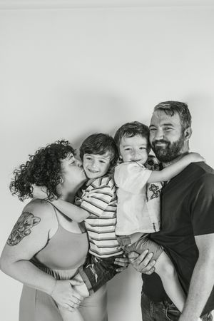 A series of black and white family photos showing playful moments and embraces between parents and children.