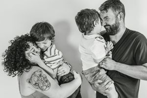 Black and white photo of two parents sharing tender moments with their young children.