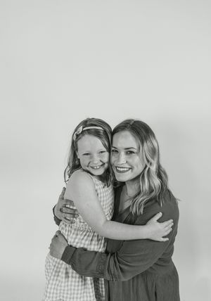 Three candid black and white photos show two people hugging and laughing joyfully against a light background.