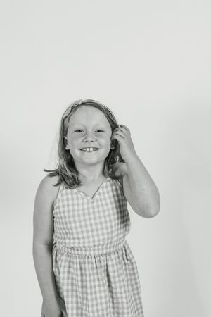 A series of three black and white photos showing a child in a checkered dress against a light background.