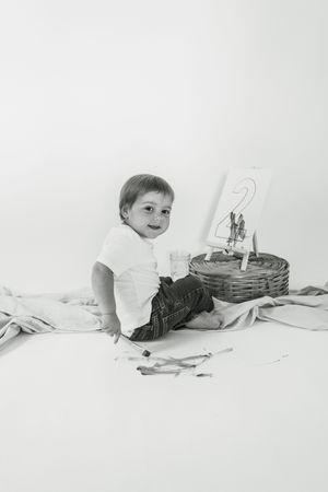 Series of black and white photos showing a baby lying on white backdrop with a basket prop.