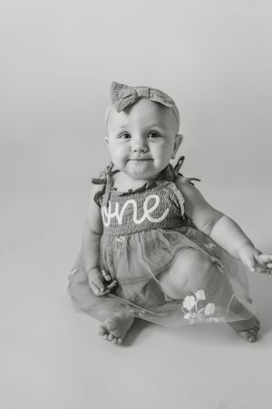 Black and white photo series of a baby in a gray romper lying on a white background.