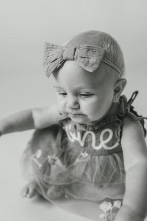 Black and white photo series showing a baby lying down in a ruffled dress against a light background.