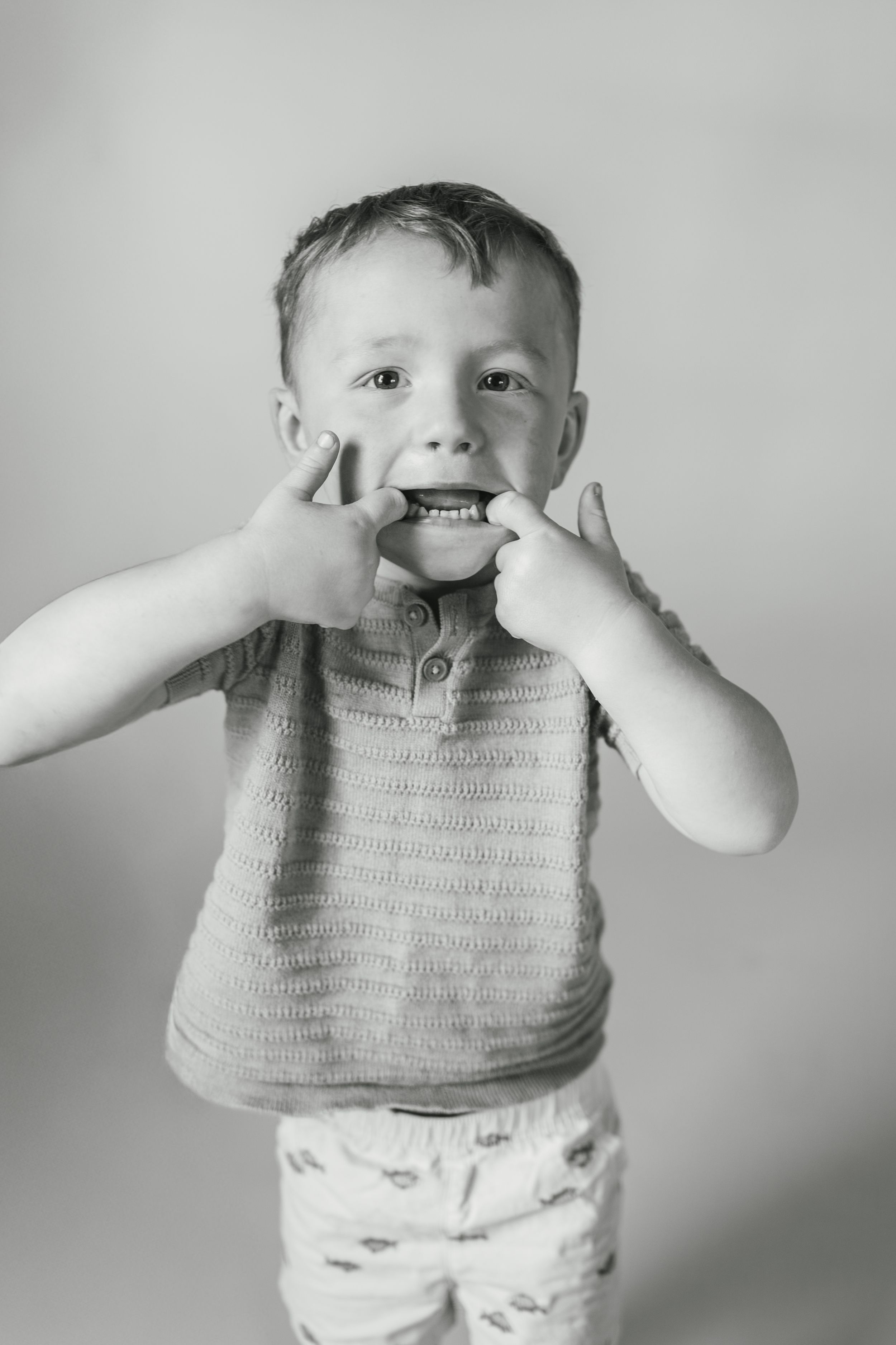Black and white photo sequence of a toddler in a knit top making silly faces and gestures.