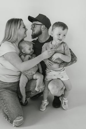 Black and white sequence of four candid family moments showing affectionate interactions between adults and toddlers.