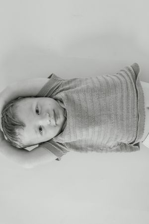 Black and white portrait series showing a baby in a knit sweater lying on a light background.