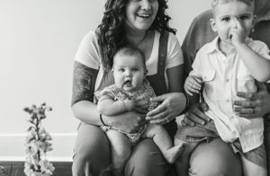A black and white candid photo of a family sharing laughs together on a couch.