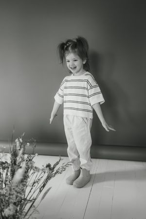 A small child in white clothing runs and plays energetically across a wooden floor in a series of action shots.
