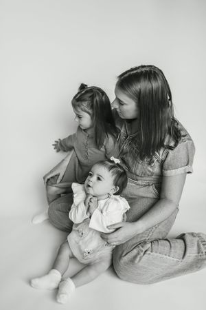 A black and white portrait shows siblings sitting together in a tender family moment.