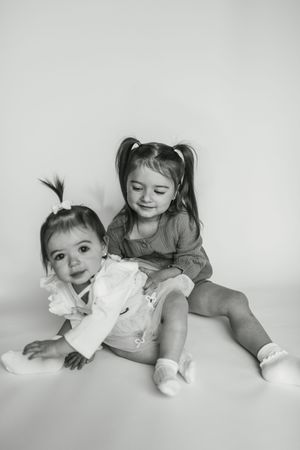 Black and white photo series showing playful interaction between siblings laying down in matching outfits.