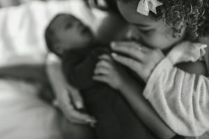 A black and white close-up photograph showing two children resting on a bed.