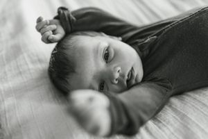 A sleeping figure rests peacefully on white bedding in a black and white photograph.