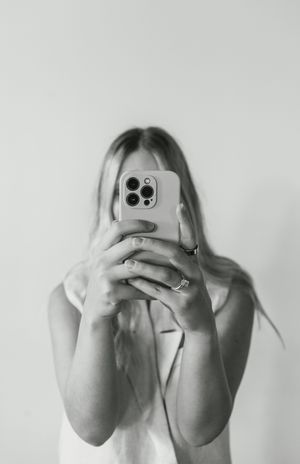 Black and white photo series of someone holding a mobile phone to take selfies against a white background.