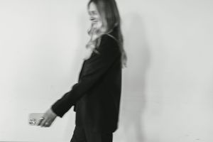 A person in a black outfit poses against a white wall in a series of candid profile shots.