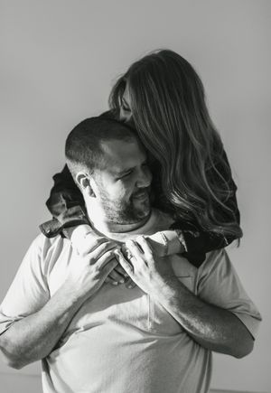 Black and white intimate portrait of a couple embracing, with the woman's long wavy hair cascading down her back.