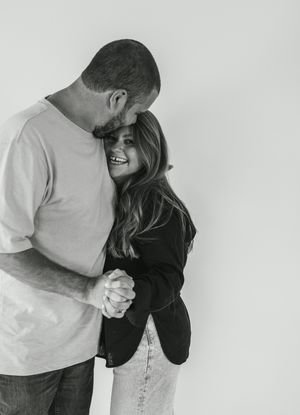 A black and white photo series shows a couple embracing and laughing together in intimate candid moments.