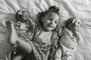 A series of black and white photos showing a baby lying on white bedding while making different facial expressions.