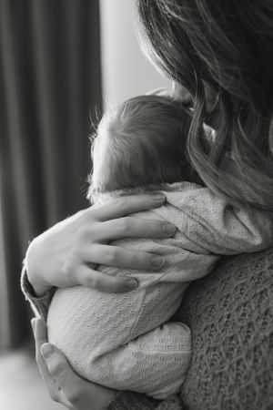 A sequence of black and white photos showing hands gently cradling a soft knit fabric in different positions.