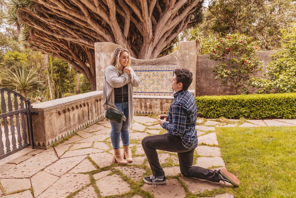 man asking woman to marry him at Casa del Herrero in Santa Barbara, ca surprise proposal on the grass