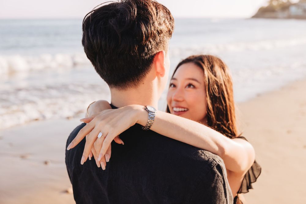 Couple embraces during romantic sunset photoshoot at a scenic beach location.