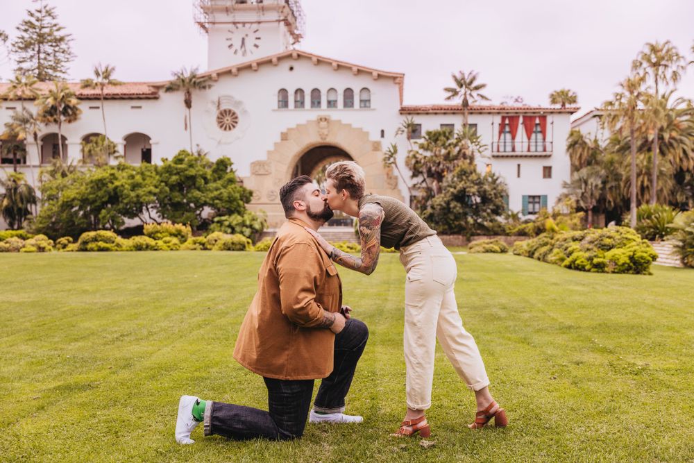 Surprise proposal on lawn in front of Spanish colonial style building.
