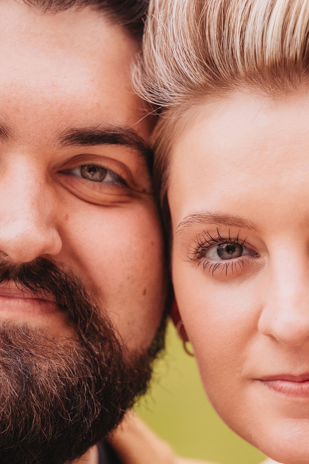 Close-up portrait of a couple with contrasting features showing half their faces against a blurred background.