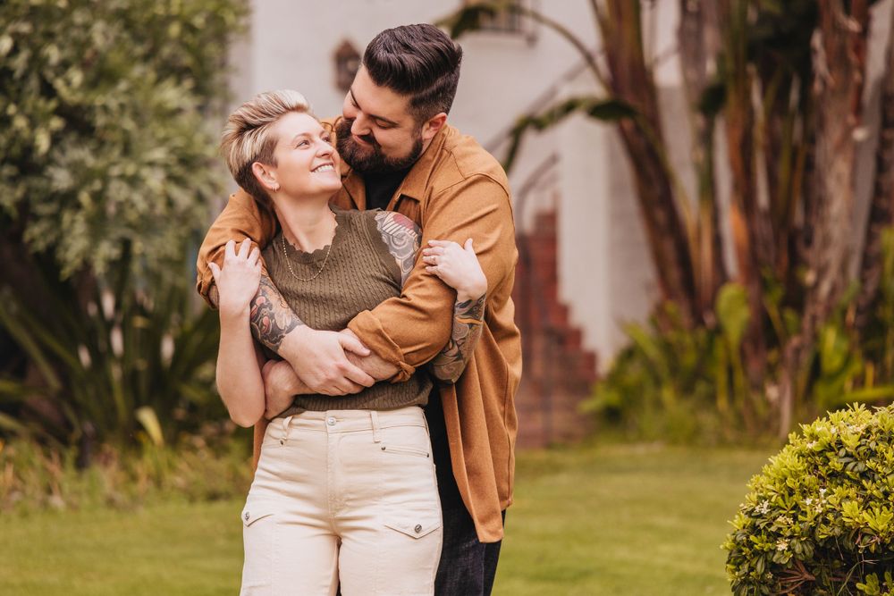 Couple sharing an intimate moment in a garden setting with lush greenery.