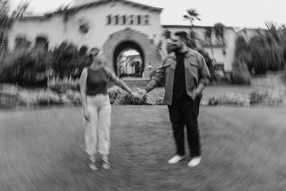 Artistic black and white photo of two people in front of a Spanish mission building.