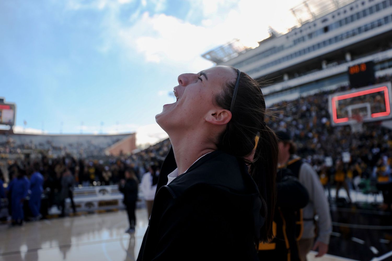A spectator reacts emotionally while watching an event in a large stadium setting.