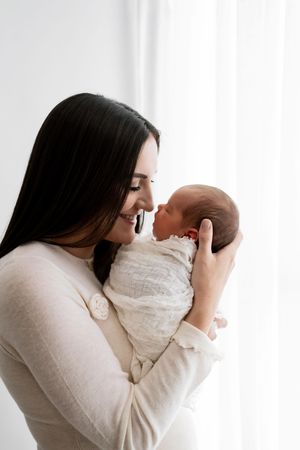 Tender moments between mother and baby captured in black and white profile portraits.