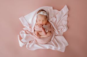 Series of serene newborn portraits with baby wrapped in soft pink blankets against rose background.