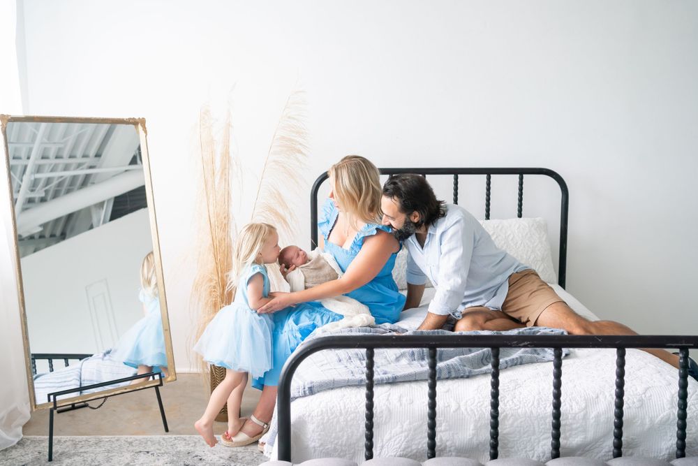 Lifestyle newborn photography session on bed with natural window light.