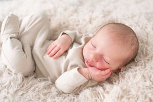 Sleeping baby peacefully posed on plush cream colored carpet during portrait session.