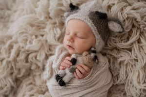 A white dog and an infant rest together in cozy white textured blankets showing companionship and comfort.