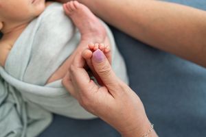 Close-up demonstration showing hands performing therapeutic massage techniques on a leg with a white towel.