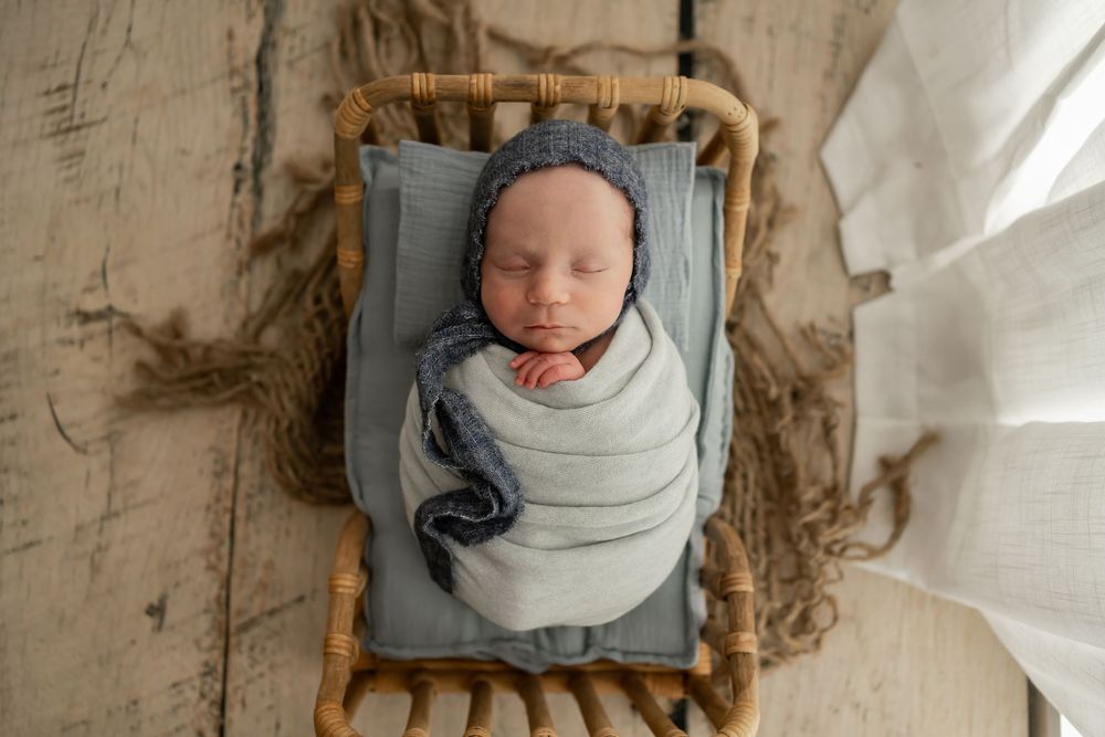 Overhead view of six newborn photography portraits arranged in frames showing baby in light swaddle on textured backdrop.