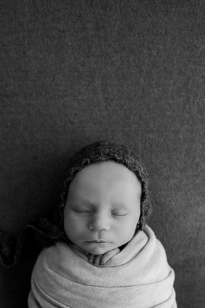 Black and white artistic newborn photography portraits with neutral tones and soft wrapping.