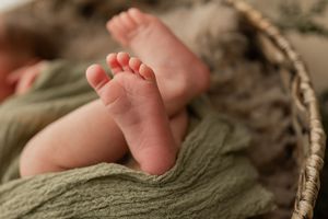 Tiny baby feet resting on a natural woven basket or wicker surface with soft focus background.