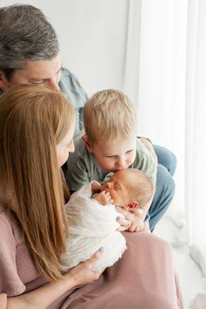 A tender family moment captured in soft natural light by a bright window.