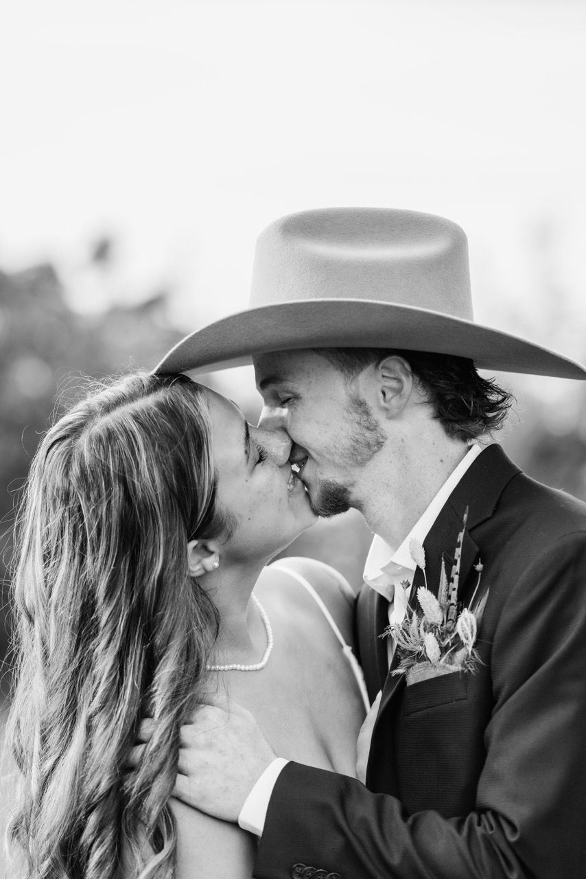 Romantic kiss under a floral archway at a Snohomish wedding. Affectionate lifestyle photography by Tim Neal.