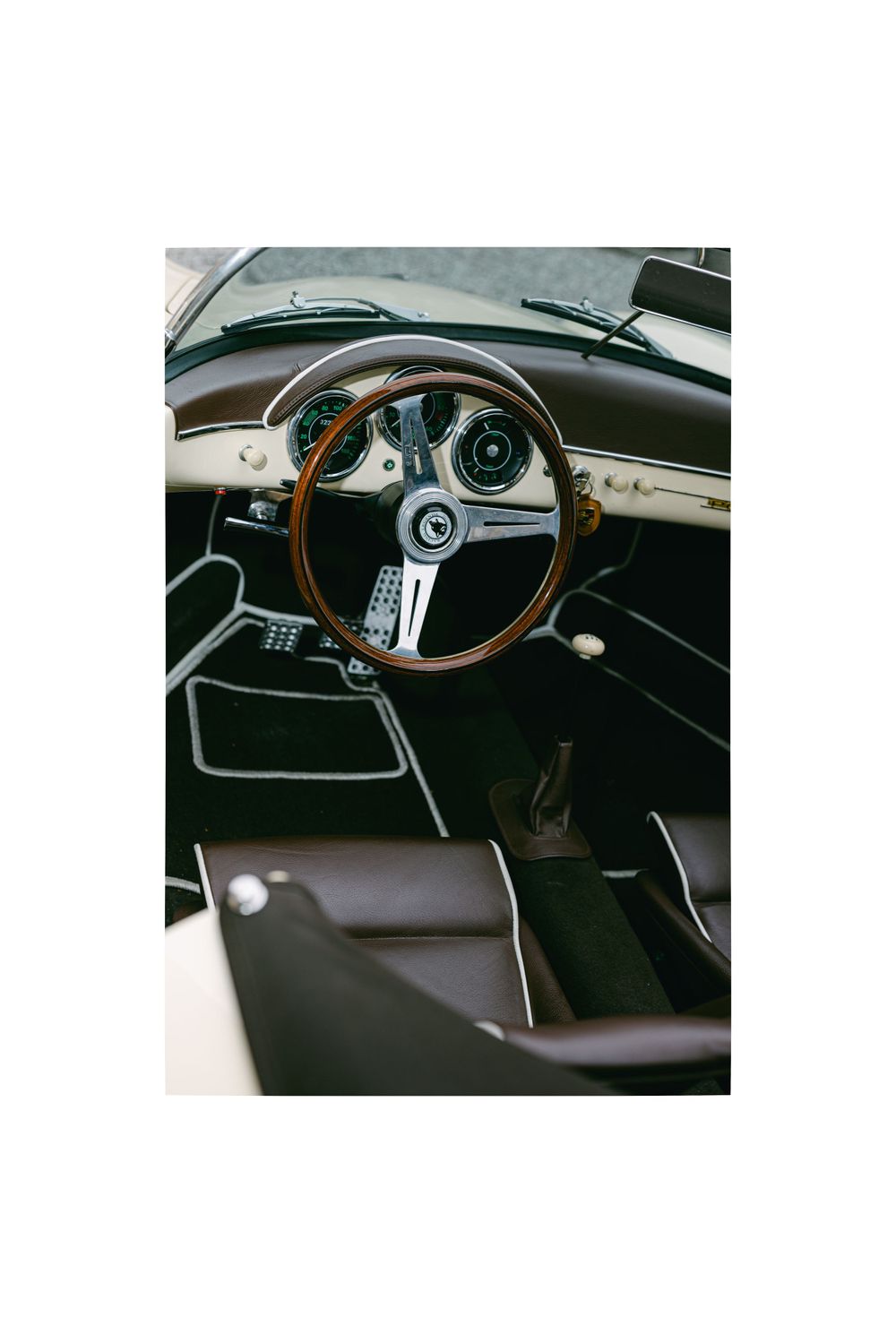 Vintage car interior showing wooden steering wheel and classic dashboard design.